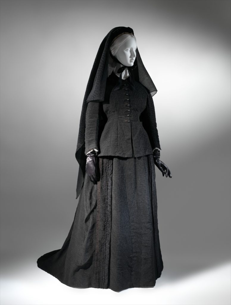 A mannequin wearing a black outfit and veil from 1874.
